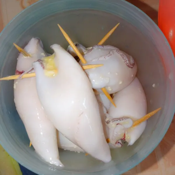 Bersihkan cumi, beri air perasan jeruk nipis, dan hancurkan tahu, campurkan dengan garam, lada, dan telur, aduk rata. Lalu masukkan ke dalam cumi, sambungkan kepala cumi dengan menggunakan tusuk gigi.