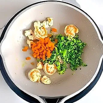 Masukkan 20 gr wortel cincang dan 30 gr brokoli cincang, aduk rata dan tumis sebentar hingga sayuran sedikit layu. Tambahkan telur orak-arik yang telah dimasak sebelumnya