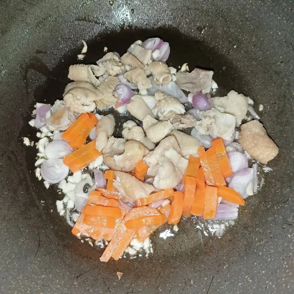 Masukkan kulit ayam dan wortel, lalu aduk-aduk sampai wortel layu dan tuangkan air.
