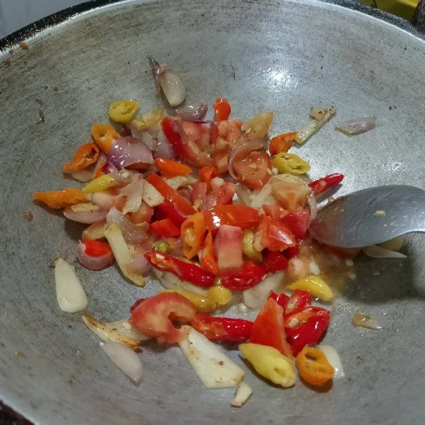 Tumis bawang merah dan bawang putih sampai wangi, dilanjutkan dengan menumis cabe dan tomat sampai layu.