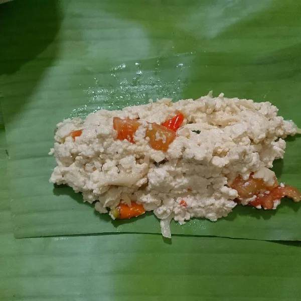 Ambil selembar daun pisang, lalu letakkan 2 sdm penuh tahu. Gulung daun pisang dan sematkan ujungnya dengan lidi.