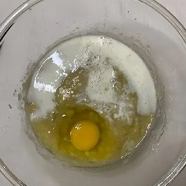Tambahkan 80 gr susu cair dan 1 butir telur ke dalam adonan pisang, lalu aduk rata menggunakan whisk
