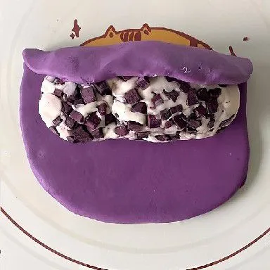 Gilas adonan ungu hingga pipih berbentuk persegi. Letakkan adonan putih berisi potongan ubi ungu di atas adonan ungu, lalu gulung hingga tertutup rapat. Bentuk menjadi roti lonjong, pastikan sambungan tertutup rapat