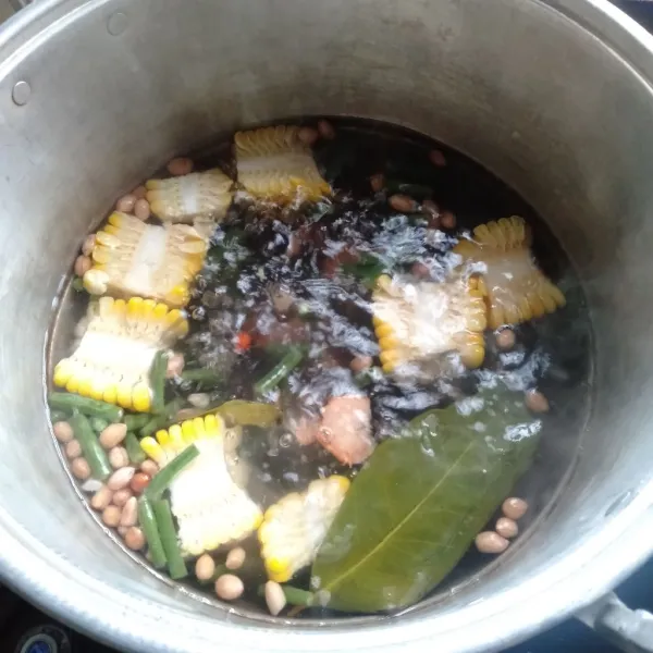 Didihkan air dan masukkan asam Jawa, lengkuas, jagung manis, terong, labu siam, kacang panjang, kacang tanah, dan daun salam masak sampai empuk