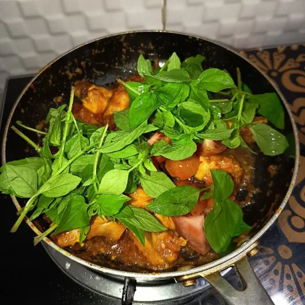 Jika airnya sudah menyusut dan bumbu meresap, masukkan kemangi beserta dengan tomat.