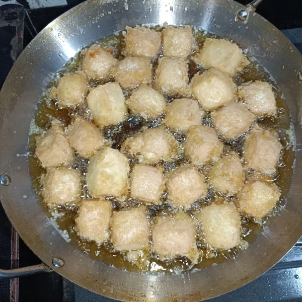 Goreng tahu sampai membentuk kulit luarnya, kemudian siram dengan adonan, ulangi hingga tepung menyelimuti
