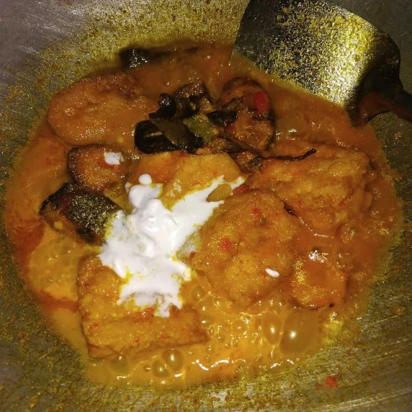 Tuangkan air, lalu tunggu sampai mendidih dan masukkan ikan dan tahu goreng. Bumbui dengan garam, kaldu bubuk, gula pasir, dan santan instan. Aduk rata.
