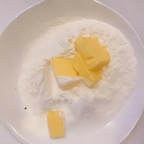 Dalam wadah lain, masukkan 200 gr terigu dan 35 gr mentega. Aduk dan remukkan mentega bersama tepung hingga membentuk butiran kecil