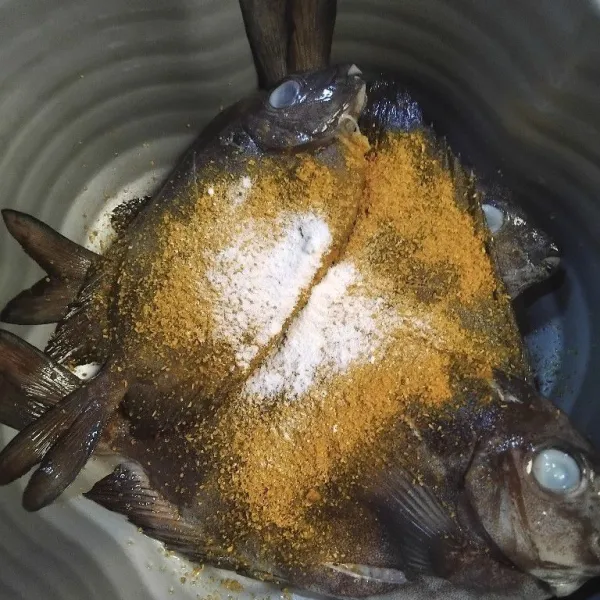 Bumbui ikan dengan garam, bawang putih bubuk, dan ketumbar bubuk, diamkan hingga bumbu meresap.