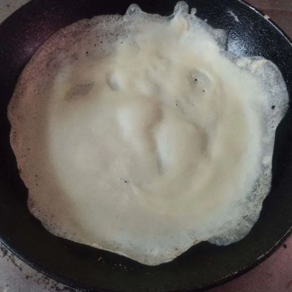 Panaskan teflon, oles margarin tipis. Tuang satu sendok sayur adonan, ratakan. Jika pinggirnya sudah mengelupas tanda kulit matang