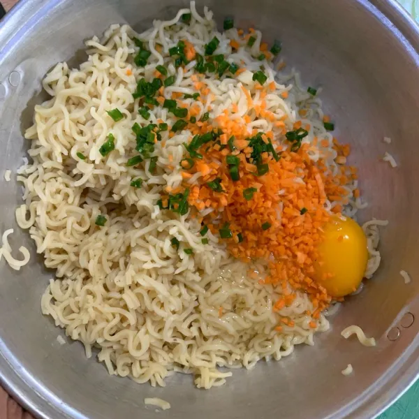 Gunting mie yang sudah direbus lalu masukan telur , wortel, daun bawang