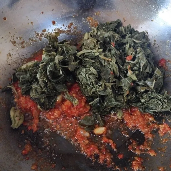 Jika bumbu sudah harum, masukkan daun singkong yang sudah dipotong-potong sebelumnya.