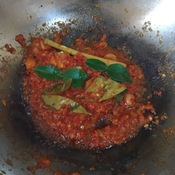 Haluskan bawang putih, bawang merah, dan cabe keriting merah, lalu panaskan minyak dan tumis bumbu. Masukkan daun salam, daun jeruk, serai, dan lengkuas sebagai bumbu aromatiknya sambil diaduk supaya tidak gosong.