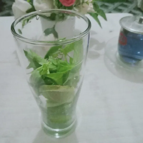 Masukkan mentimun, jeruk nipis, dan daun kemangi ke dalam gelas saji.