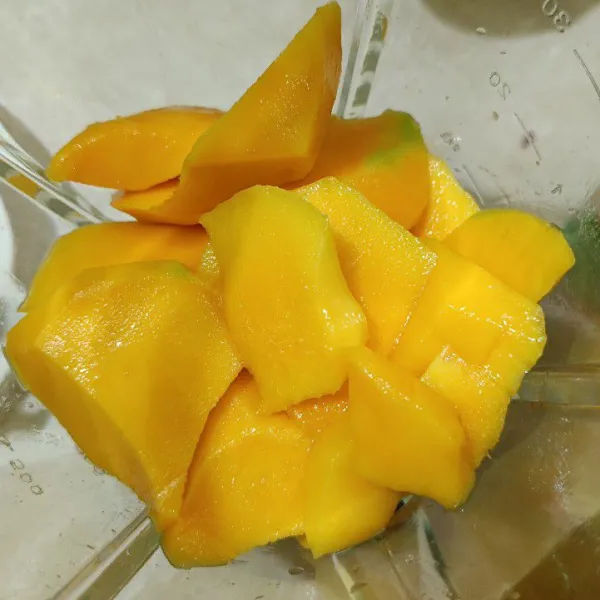 Kupas dan potong buah mangga, masukkan ke dalam blender