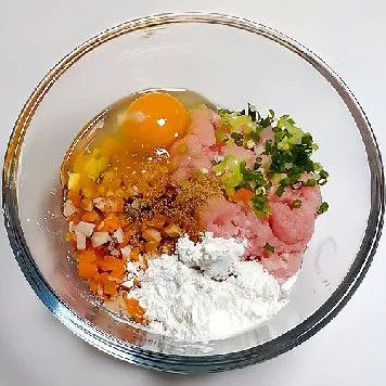 Masukkan 300 gr daging babi cincang. Tambahkan wortel dan jamur cincang, 20 gr daun bawang, 3 gr garam, 1 butir telur, 15 gr maizena, 10 ml minyak wijen, dan 5 ml kecap asin