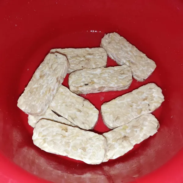 Marinasi tempe dengan bawang putih, garam, dan penyedap rasa.