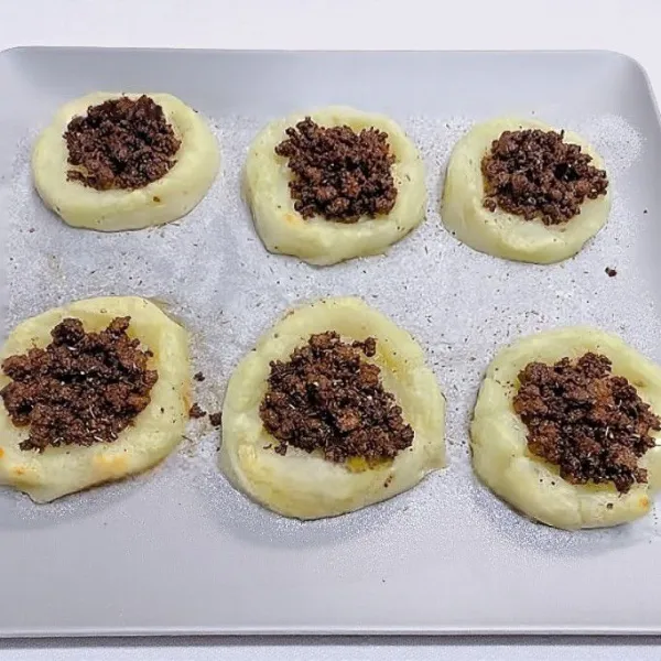 Letakkan di loyang, panggang suhu 190°C selama 10 menit. Tambahkan sekitar 20–25 gr isian daging ke tengah tiap kentang lalu panggang lagi selama 5 menit pada suhu 190°C