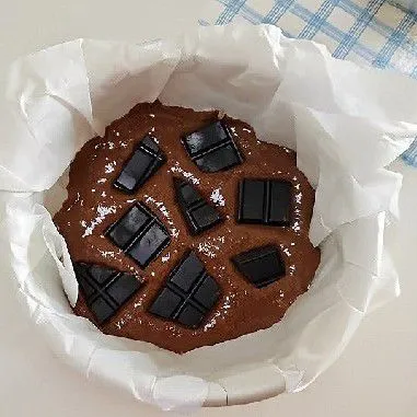 Tuang setengah adonan ke dalam loyang yang telah dialasi baking paper, lalu beri isian 40 gr cokelat batang. Tuang sisa adonan di atasnya dan ratakan