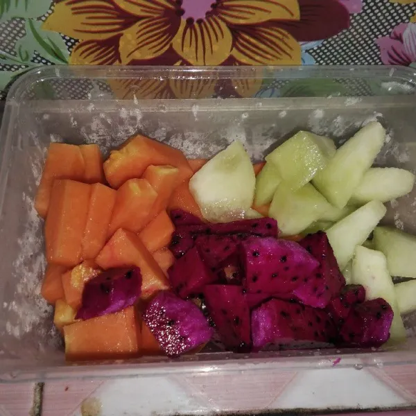 Potong-potong menjadi bagian-bagian kecil buah pepaya, melon, dan buah naga.