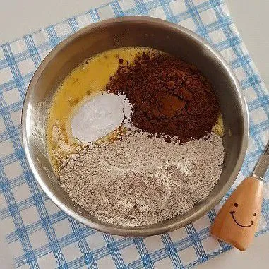 Masukkan 100 gr tepung gandum utuh, 20 gr bubuk kakao, dan 7 gr baking powder. Aduk kembali hingga semua bahan kering tercampur rata