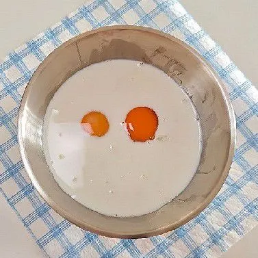 Tambahkan 2 butir telur ke dalam lumatan pisang. Tuang 120 ml susu cair ke dalam mangkuk. Aduk semua bahan basah tersebut hingga tercampur rata