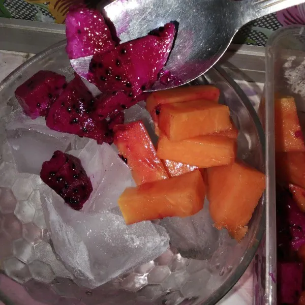 Masukkan potongan buah naga, pepaya, dan melon di atas es batu.